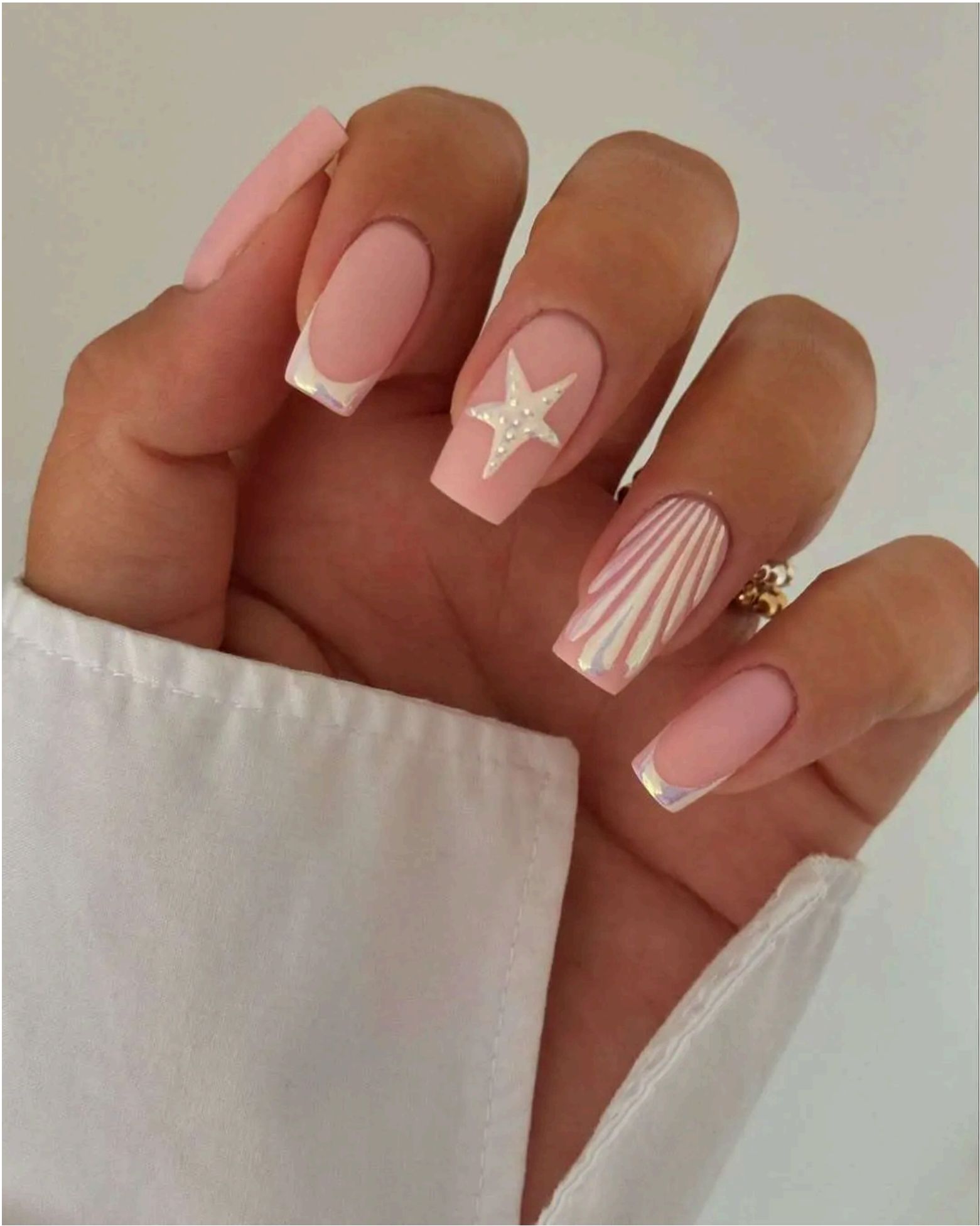 Pink base with seashell patterns, French tips, and a pearly starfish accent – peak coastal chic.