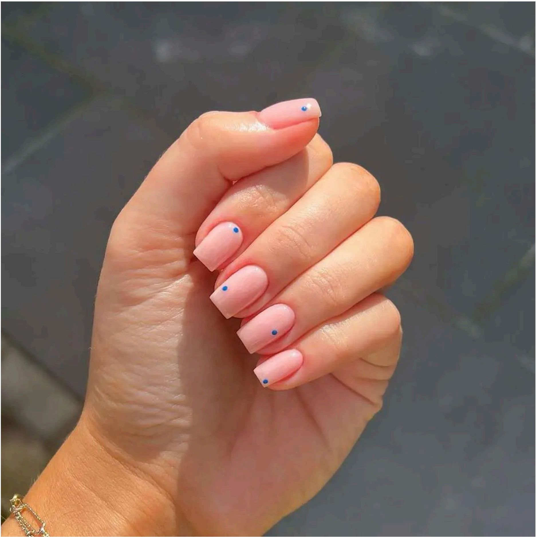 Peachy pink nails with tiny blue dots – minimal beach vibes done right.