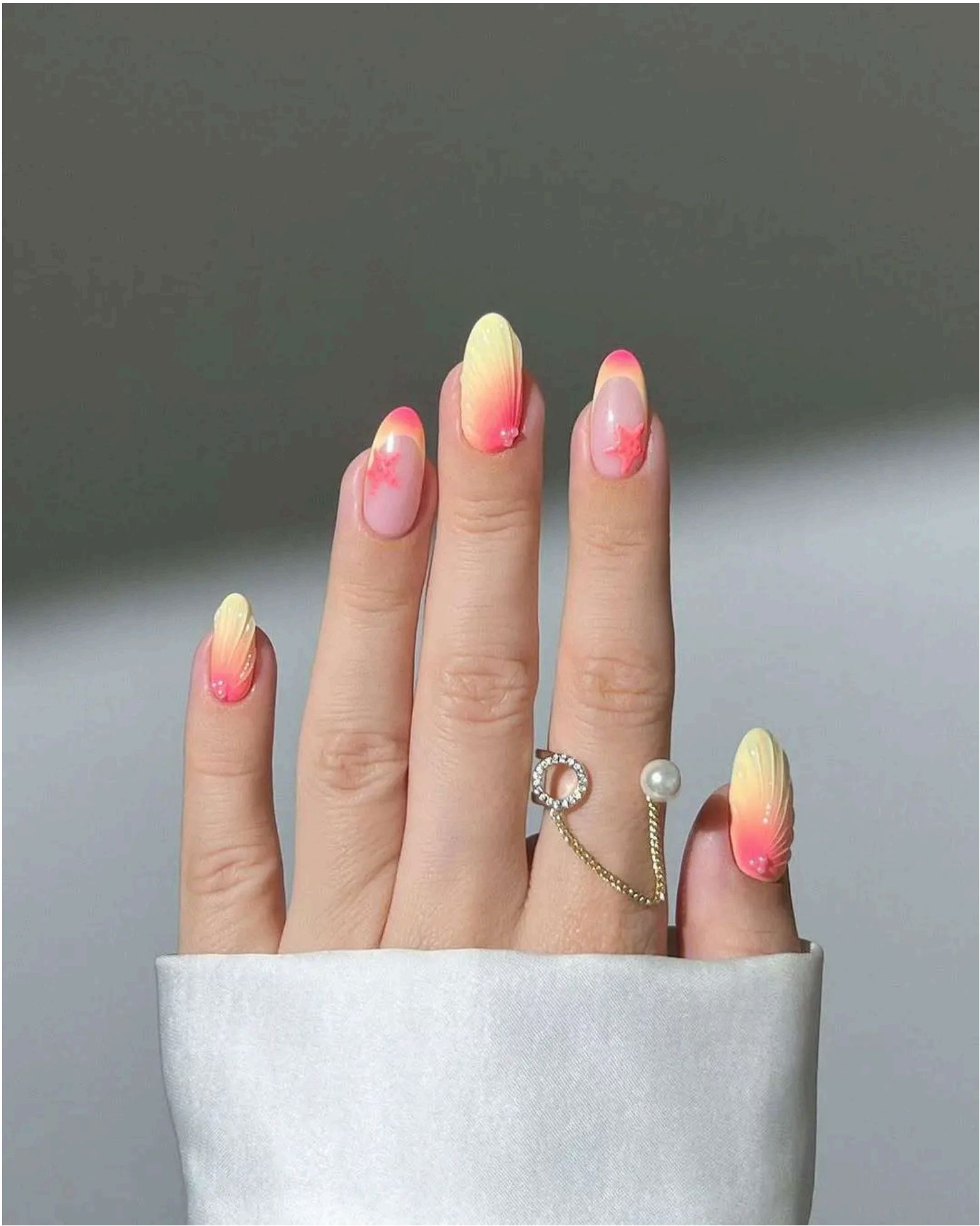 Pink nails with coral and yellow gradient tips plus tiny starfish details – serving pure beachside sunset magic.